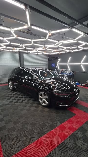 VW Golf preto finalizado no estúdio com reflexo das luzes hexagonais