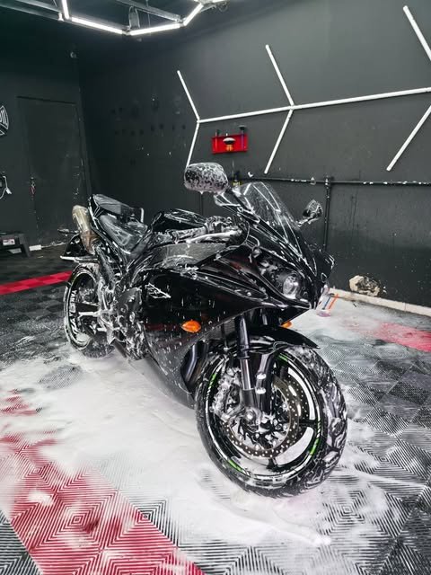 Moto esportiva preta coberta de espuma no estúdio